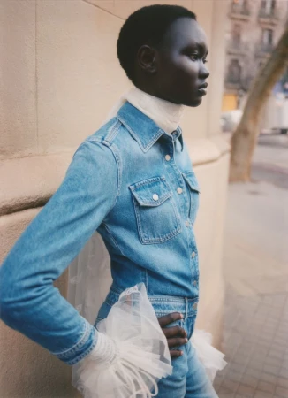 Model Ateta Jok wearing a blue denim shirt and jeans with white tulle cuffs for Vogue Polska photographed by Pía Riverola.