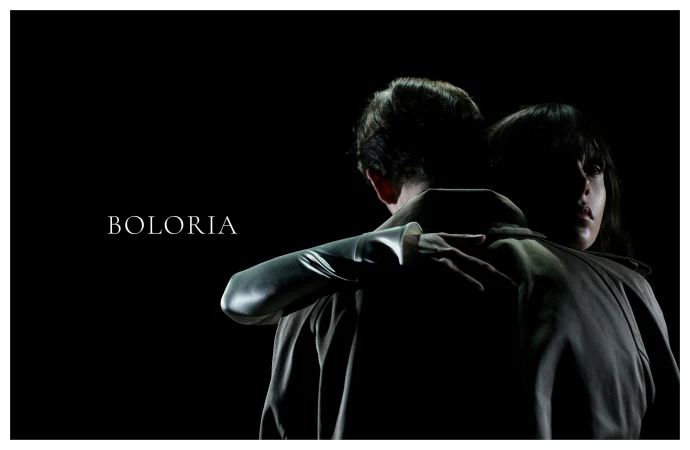 Man and woman embracing closely in a dark studio setting with selective high-contrast lighting for the Boloria ad campaign.