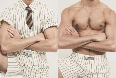 Two male models standing side by side against a white background, one wearing a striped shirt and shorts with a tie