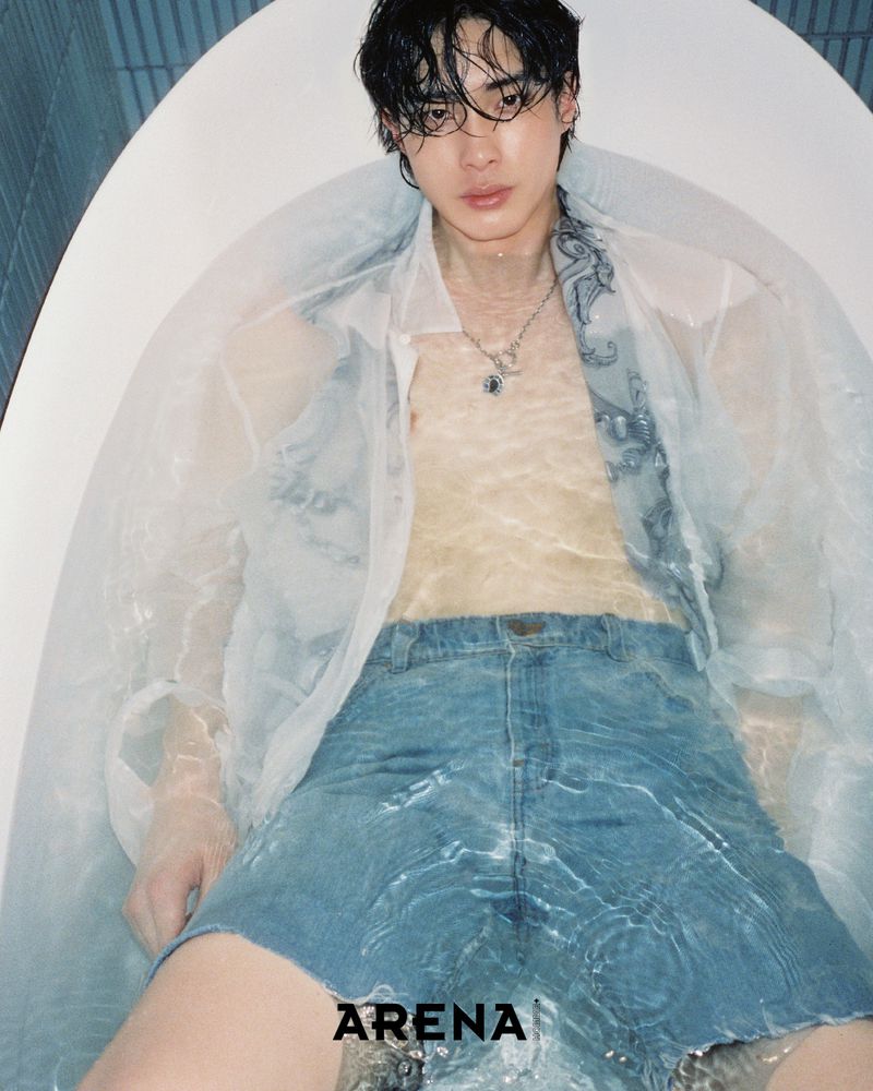 Young man in a bathtub, wearing jeans and a transparent shirt. Shot in a light-filled, indoor setting for Arena magazine.