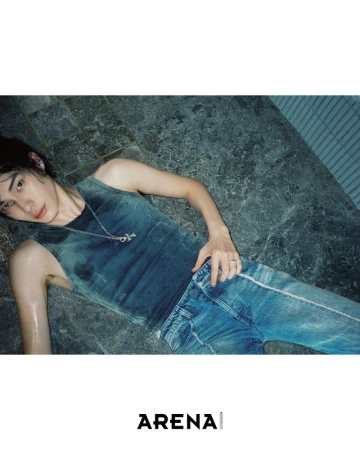 Jinyeong Pak lying on wet stone tiles wearing a faded teal tank top, blue jeans, and silver necklace for Arena Homme+ Korea.