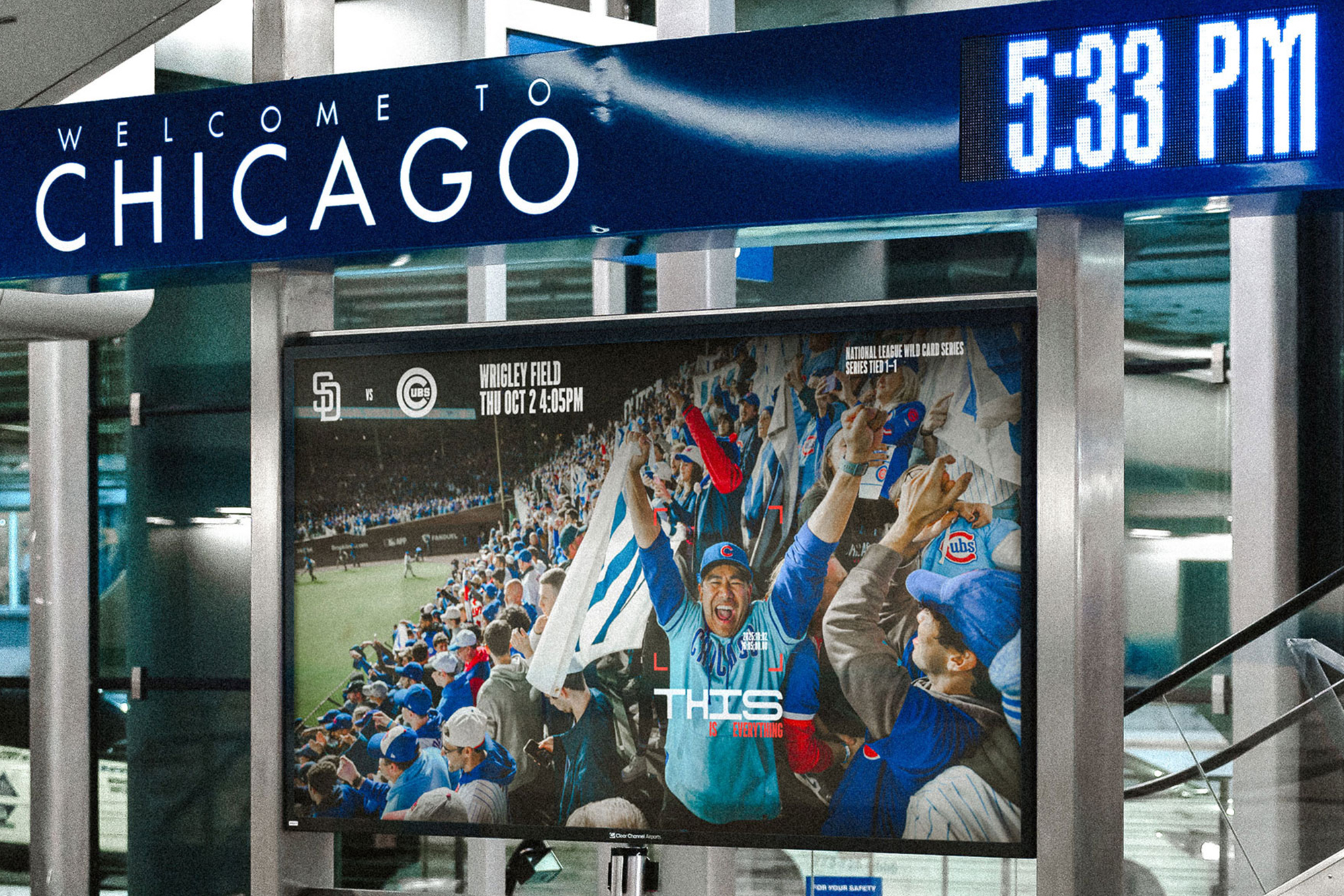 A digital transit billboard displaying a Chicago Cubs baseball game announcement under a Welcome to Chicago sign with a digital clock.