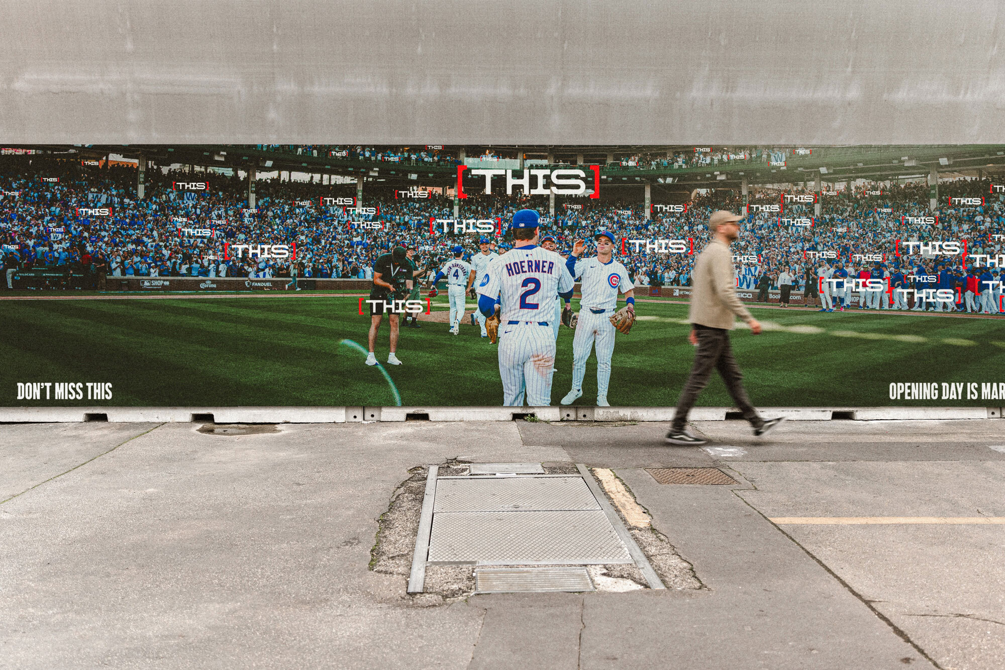 Pedestrian walking past an outdoor Chicago Cubs billboard displaying baseball players on a stadium field.