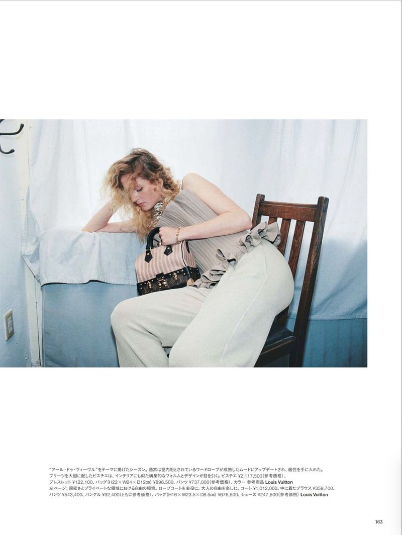 Model Thialda Bok seated on a wooden chair holding a striped handbag for Harper's Bazaar Japan