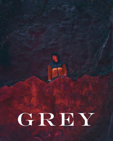 Model Federico Battisti behind a dramatic red-lit rocky ledge wearing a colorblock hooded jacket for Grey Magazine.