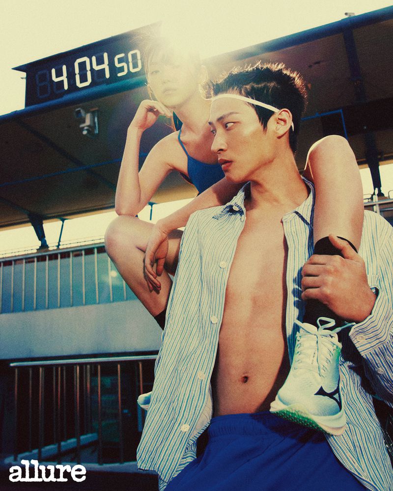Athletic fashion shoot outdoors with an adult male carrying an adult female on his shoulders, wearing casual clothes and athletic shoes.