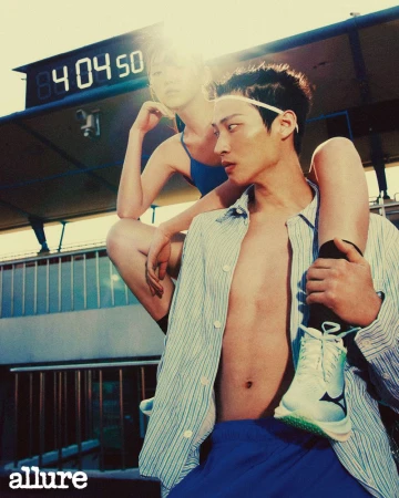 Athletic fashion shoot outdoors with an adult male carrying an adult female on his shoulders, wearing casual clothes and athletic shoes.
