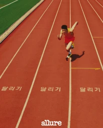 A male model running on a red running track with white lane lines and Korean text printed on the track surface.