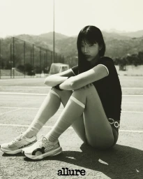 Model seated on an outdoor track wearing white running shoes and knee-high socks for Allure Korea
