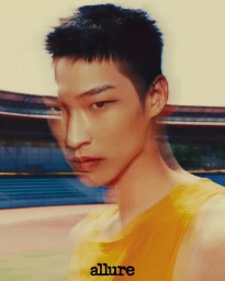 Close-up portrait of a male model with multiple exposure motion blur wearing a yellow tank top outdoors at a stadium.