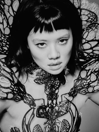 Portrait of a woman with dark hair and fringe wearing an intricate black lace collar for Numero Netherlands