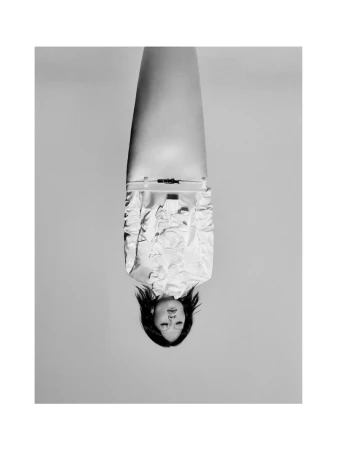 Inverted black and white portrait of an East Asian woman wearing a textured ruffled shirt against a seamless studio backdrop.