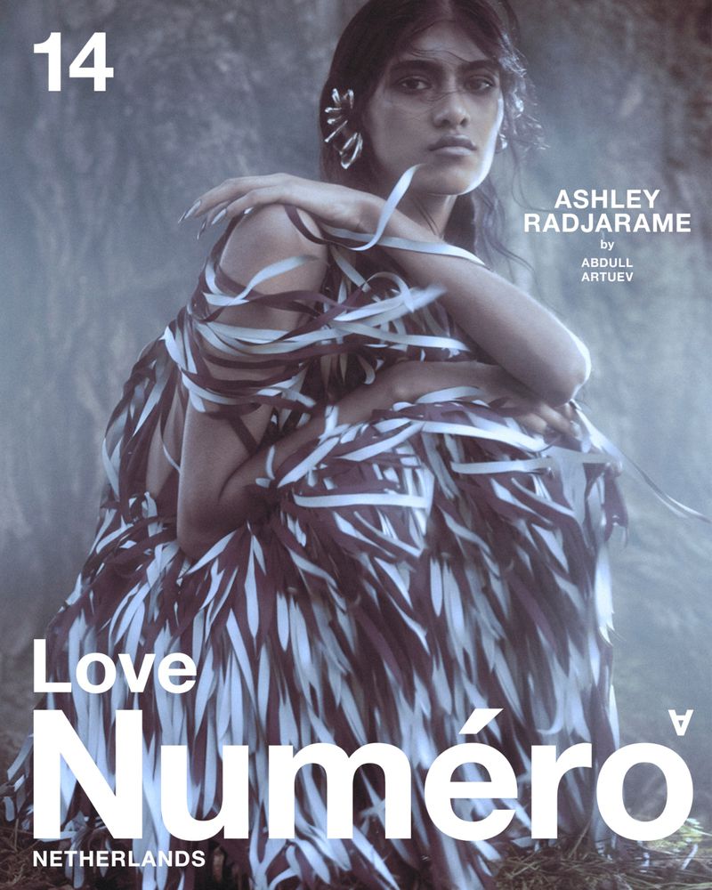 Fashion magazine cover featuring a posed adult female model wearing a dress made of ribbons against a misty background.