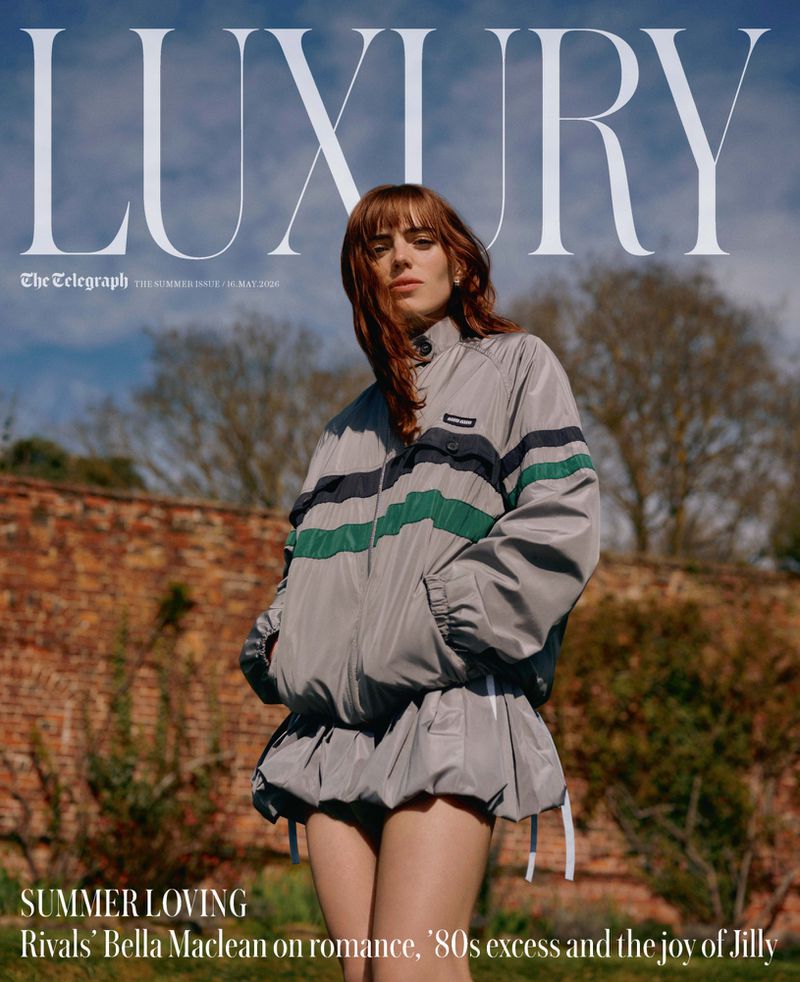 Magazine cover featuring a young woman in a grey and green tracksuit, posing outdoors against a brick wall and foliage under a cloudy sky.