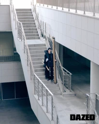 Model standing on outdoor concrete staircases holding a long rectangular cardboard tube in a Dazed & Confused Korea fashion editorial
