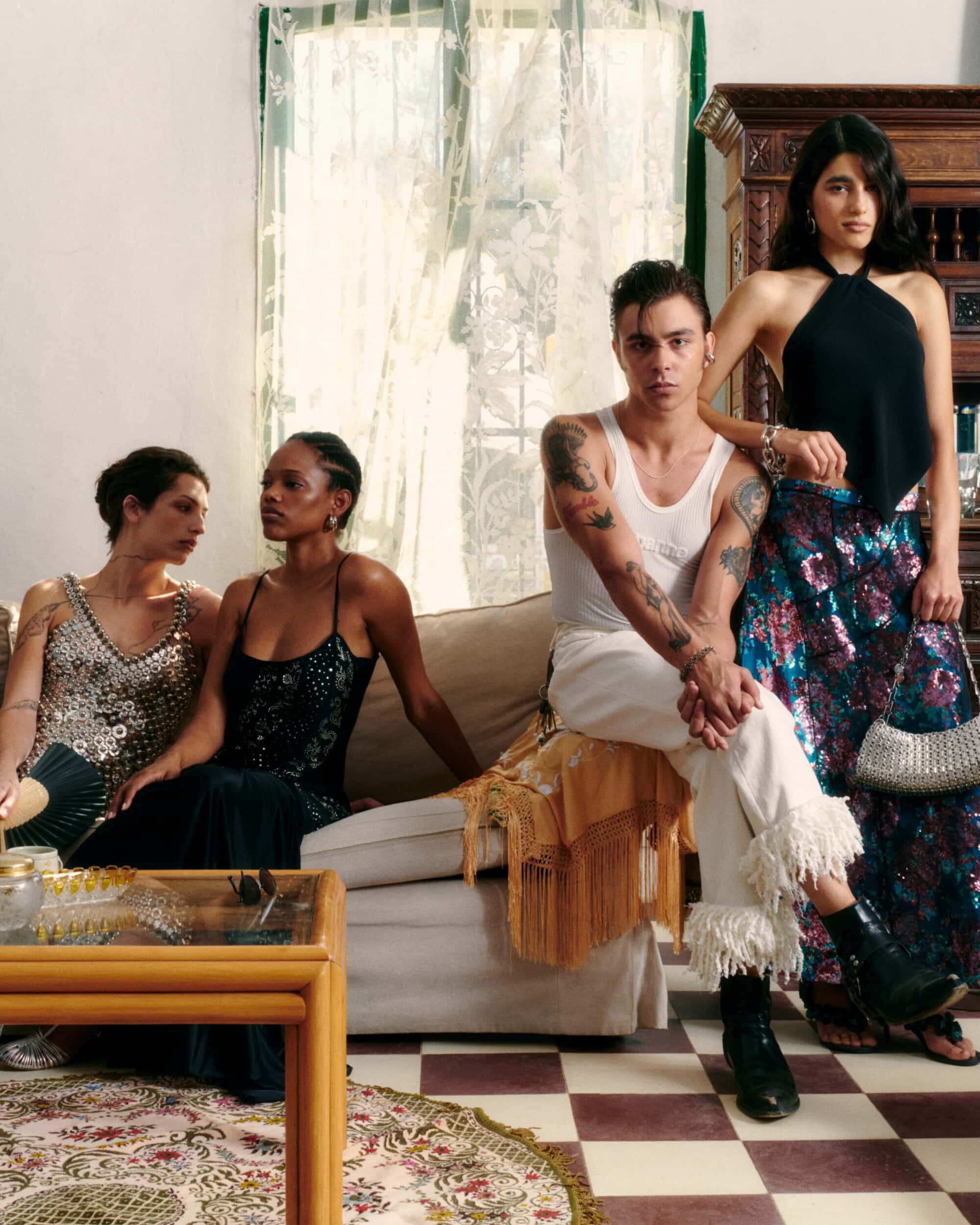 Four models posed together in a living room, seated on a couch and standing next to a dark wood cabinet, for Rabanne.