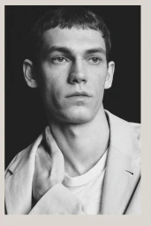 Portrait of a male model wearing a light blazer and white t-shirt against a dark background for Massimo Dutti Limited Edition S/S 26