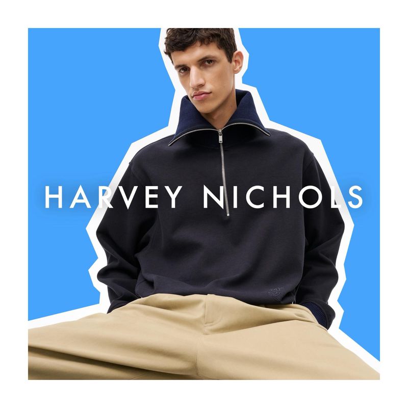 Model Youssef Rocha wearing a black half-zip sweater and beige trousers against a blue backdrop for Harvey Nichols.