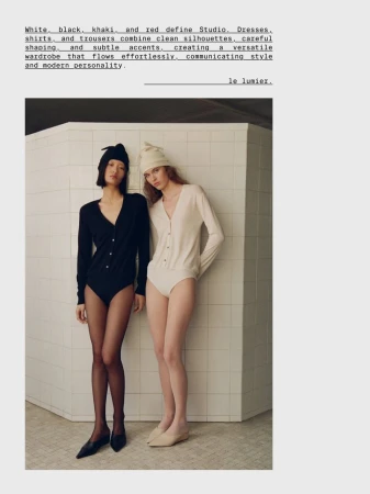 Two models in black and cream knit bodysuits and matching beanies standing against a tiled partition wall.