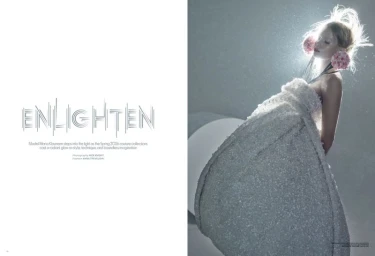 Model Maria Klaumann wearing a sculptural textured white gown with pink floral ear accents on a magazine spread titled Enlighten.