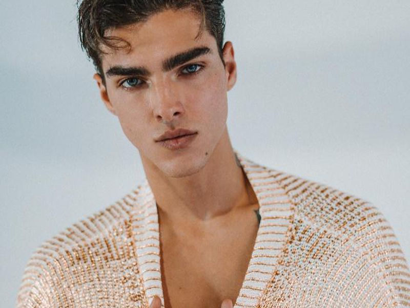 Model Simone Stravolo wearing a textured knit cardigan against a neutral studio backdrop.