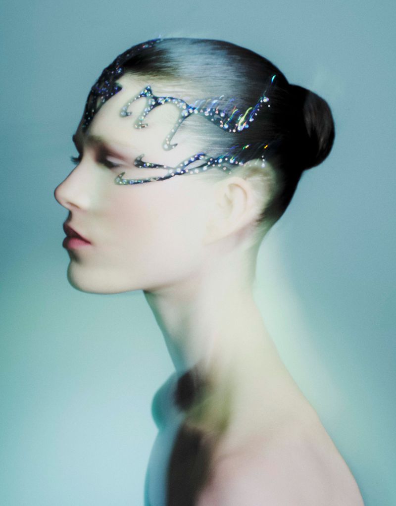 Profile portrait of a woman with sleek dark hair in a bun and crystal face ornaments for A Magazine Curated By editorial