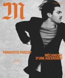 Portrait of Panayotis Pascot wearing a dark suit jacket and striped shirt for M Le magazine du Monde