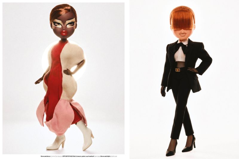 Two fashion dolls styled in high-fashion designer outfits, one in a sculptural dress and one in a black suit, on white backgrounds.