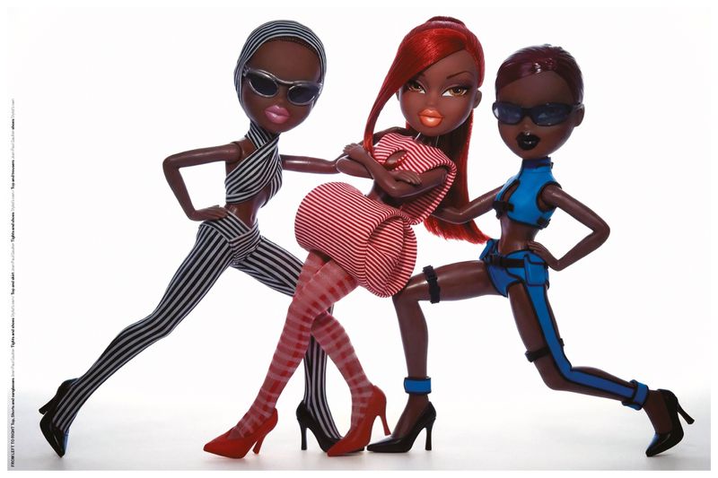 Three fashion dolls in high-concept striped and blue outfits wearing sunglasses and high heels against a white studio background.