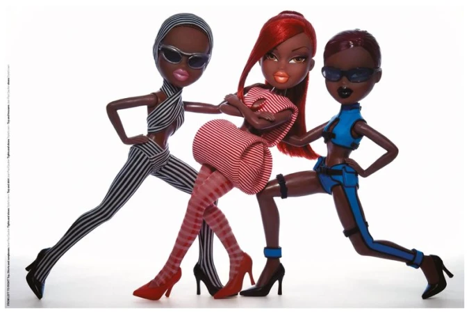 Three fashion dolls in high-concept striped and blue outfits wearing sunglasses and high heels against a white studio background.