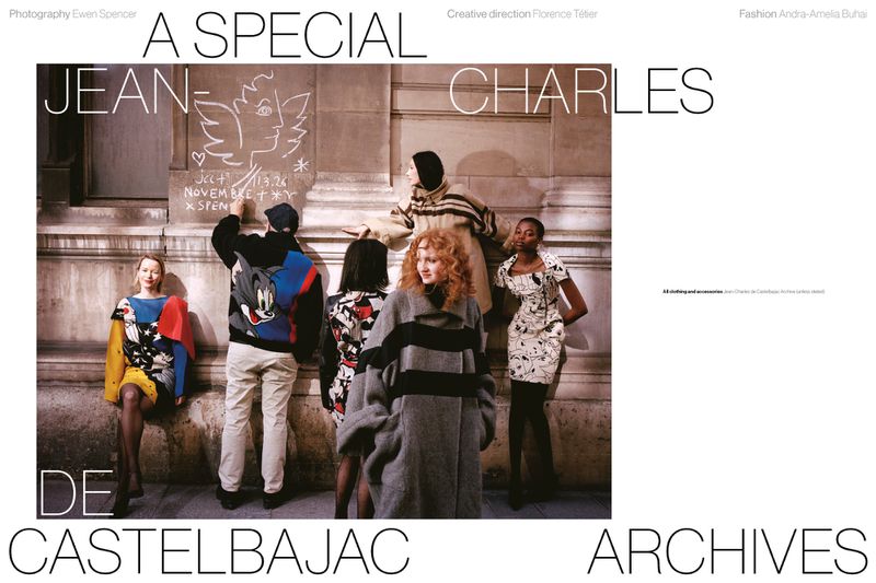 Models in archival Jean-Charles de Castelbajac garments gathered outside while a man draws on a stone building facade.