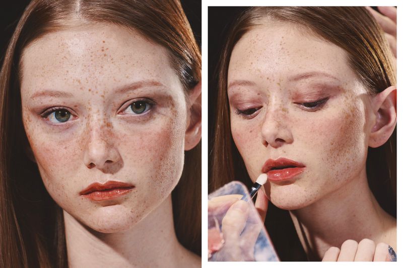 Close-up beauty portraits of a model with heavy freckles and glossy lips during makeup application for Novembre Magazine.