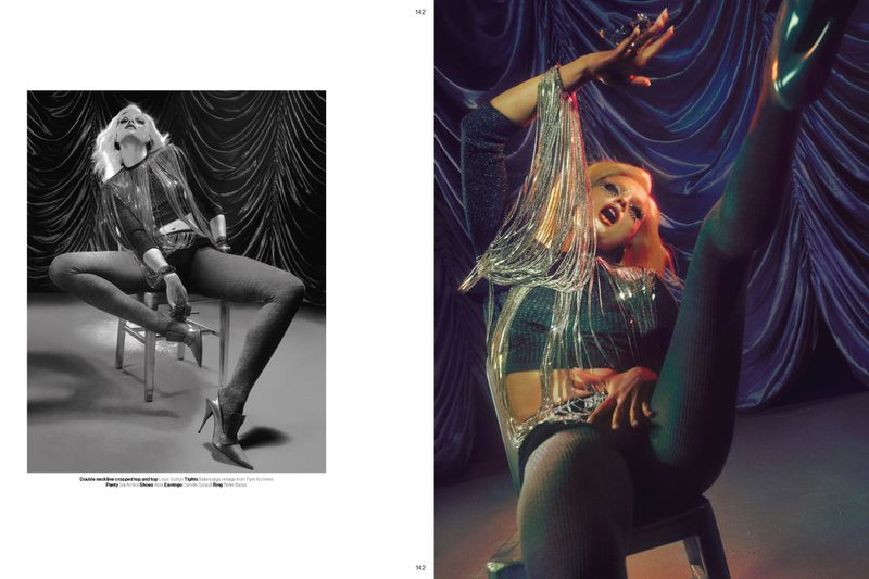 Model Fran Summers wearing a metallic fringe top and heels, posing dynamically on a chair for Novembre Magazine.