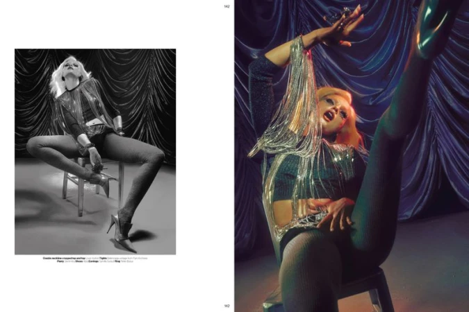 Model Fran Summers wearing a metallic fringe top and heels, posing dynamically on a chair for Novembre Magazine.