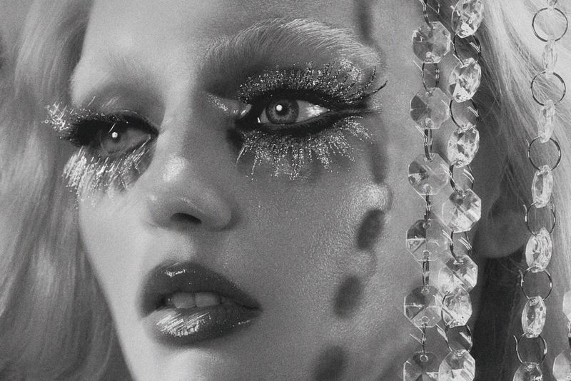 Close-up black and white portrait of model Fran Summers with dramatic glitter eyelashes and hanging crystal strands.