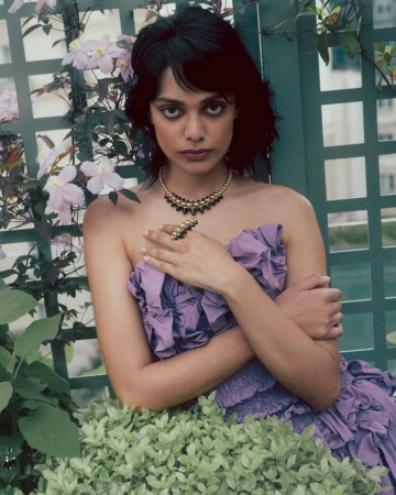 Model Zinnia Rose wearing a purple dress and beaded necklace against a garden trellis for Elle India