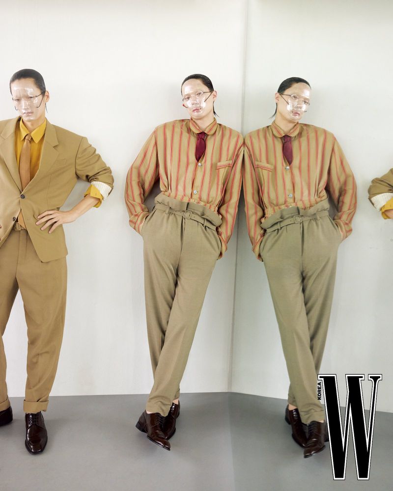 Model Jinyeong Pak posing in a striped shirt and high-waisted trousers with mirror reflections against a neutral studio backdrop.