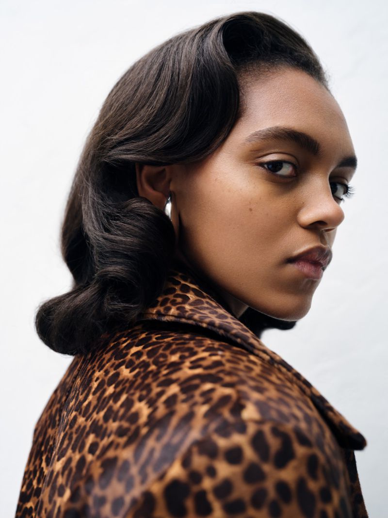 Close-up portrait of model Bebe Parnell in a leopard print jacket with retro wave hairstyle against a white backdrop