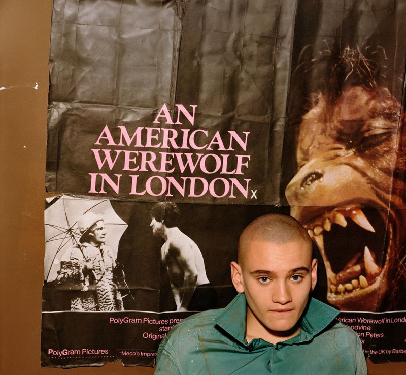 A young man with a buzz cut in a green collared shirt standing in front of an An American Werewolf in London poster.
