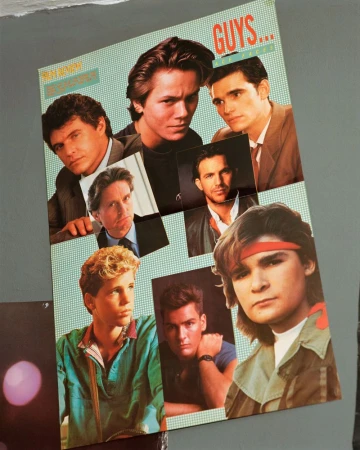 Vintage magazine poster collage featuring 1980s actors including River Phoenix, Matt Dillon, and Corey Feldman pinned to a wall.