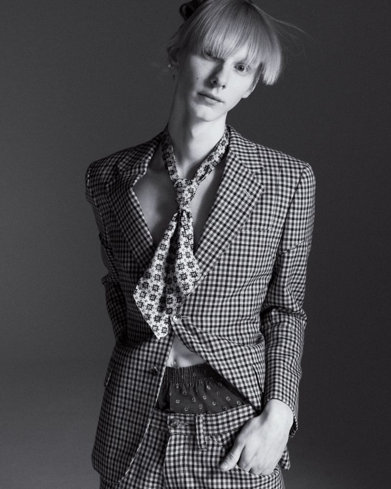 Model Nik Dermendzhiev wearing a gingham check suit and neck scarf in a black and white portrait for Arena Homme +.