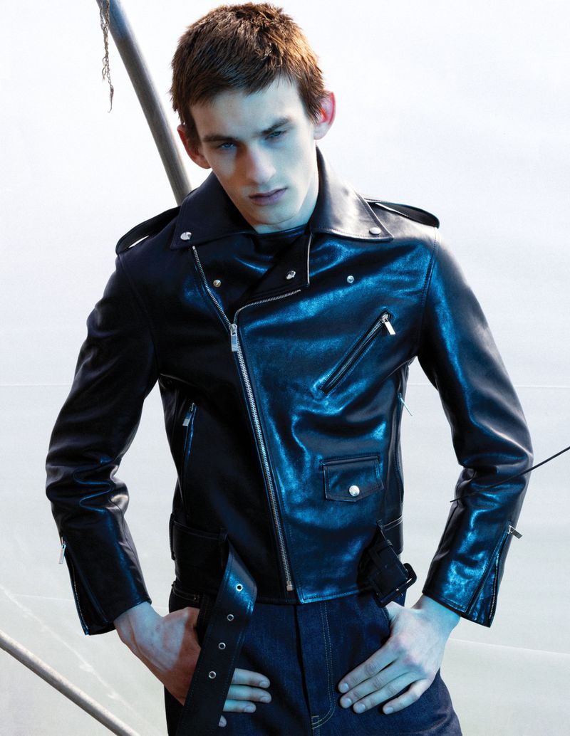 Model Joe Bottomer posing in a fitted black leather motorcycle jacket with silver zippers and dark denim jeans.
