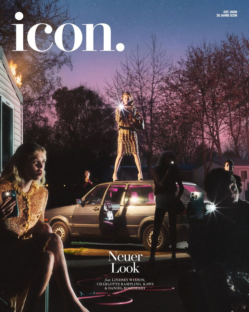 Magazine cover featuring a woman standing on a car with others holding phones, set against a dusk sky, and a house with a small fire.