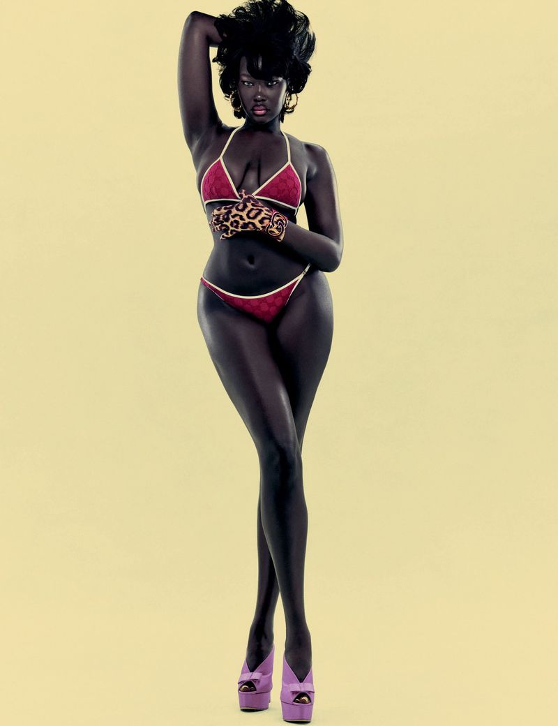 Woman in bikini and platform shoes posing against yellow background in studio lighting, fashion and beauty editorial shot.