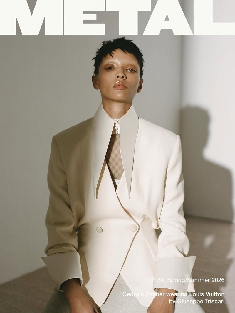 Fashion magazine cover features an adult female model wearing a cream blazer and patterned tie, in a photo studio setting with neutral colours.
