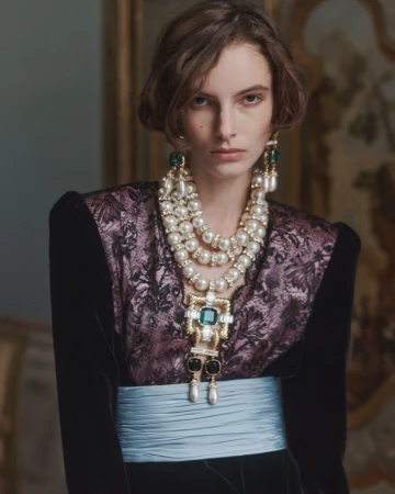 Model Saar Mansvelt Beck wearing layered pearl necklaces, drop earrings, and a brocade bodice with light blue sash for Valentino.
