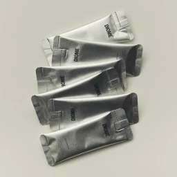 A staggered vertical stack of silver metallic foil packaging sachets printed with the Diome logo on a neutral off-white background.