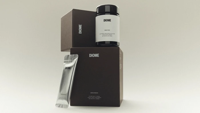Diome supplement packaging featuring a dark capsule jar, liquid supplement sachet, and branded brown boxes on a light seamless backdrop.