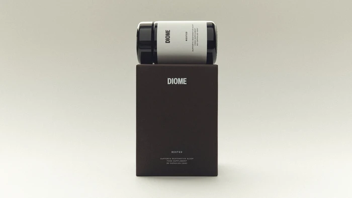 Diome Rested supplement bottle resting horizontally on its dark brown rectangular product box against a pale neutral background.