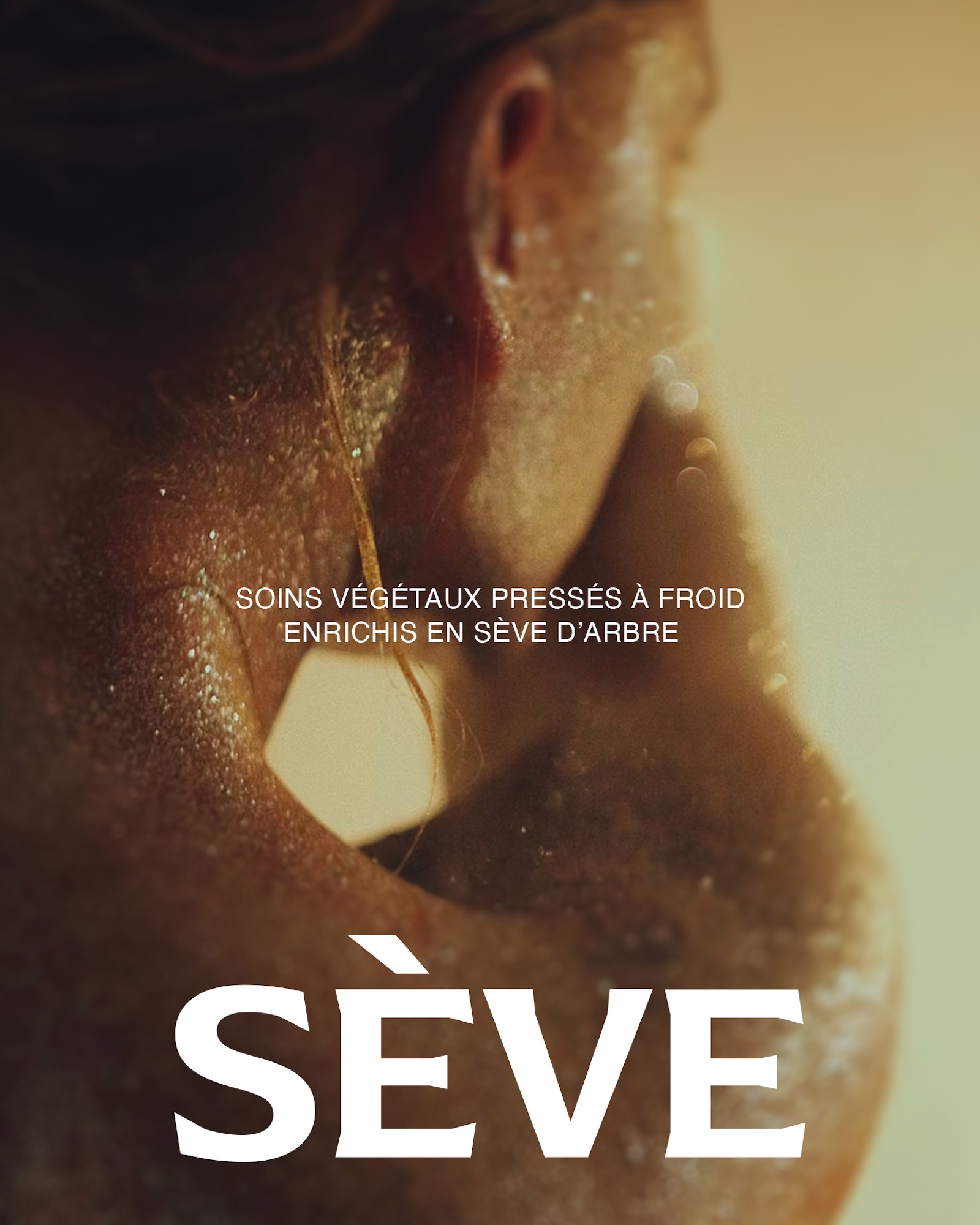 Close-up of wet glistening skin covered in water droplets with Sève typography in warm golden lighting.